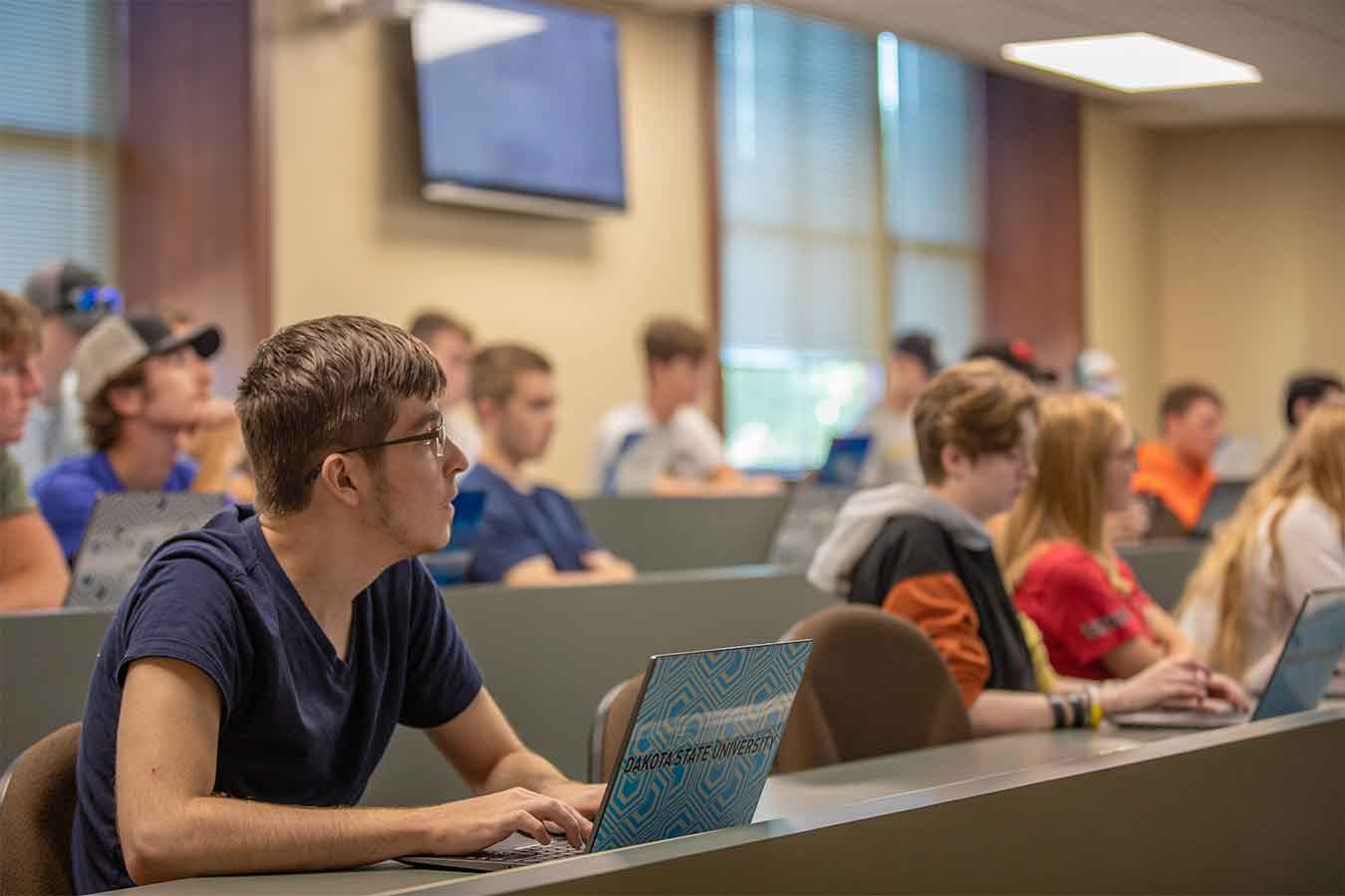 Students sitting in a classroom with their computers.