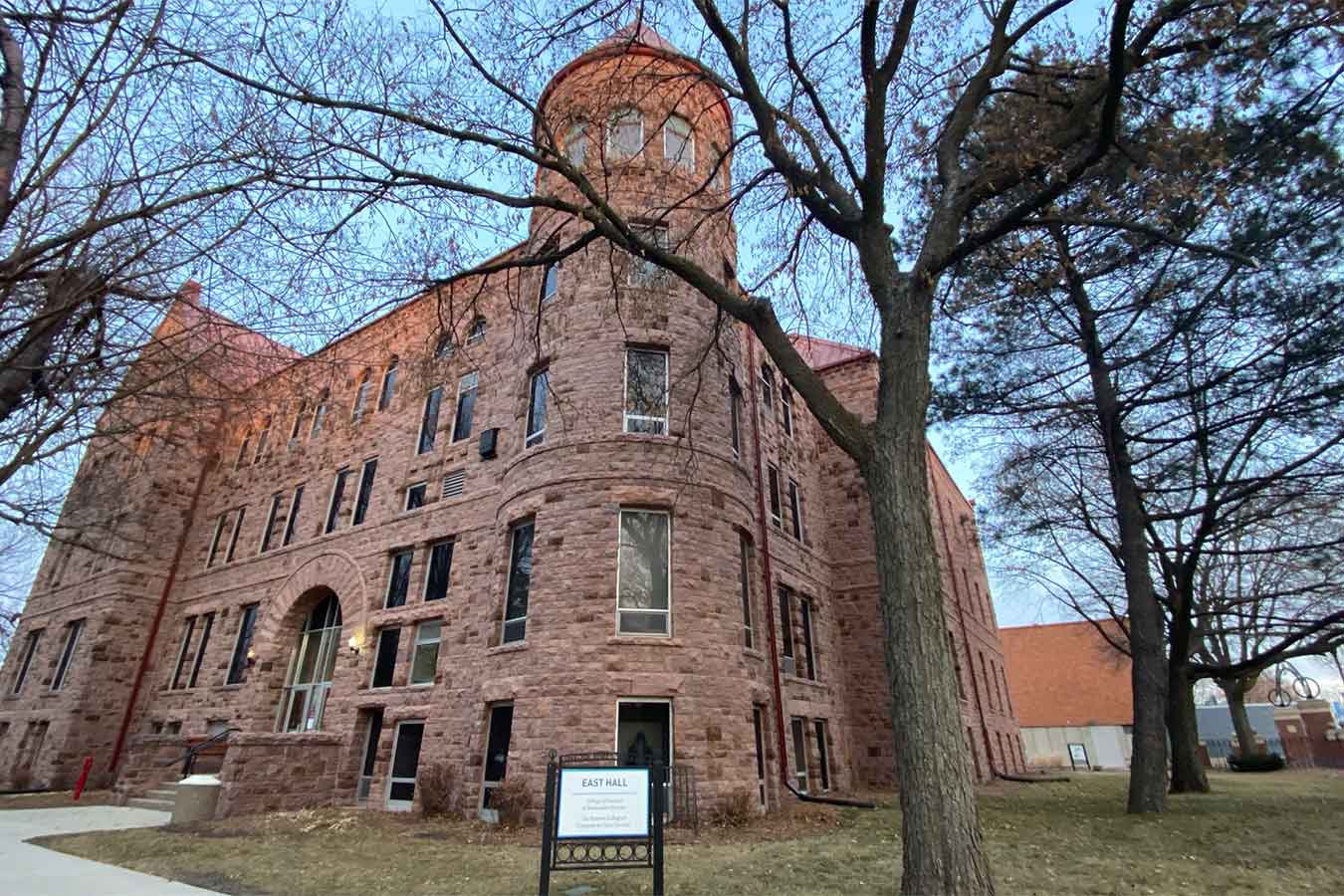 Image of East Hall with bare trees around it and a blue sky.